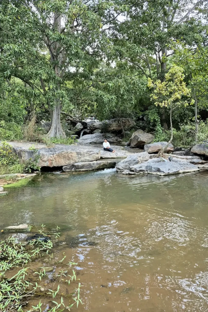 Shruti sitting on the banks of a river flow near Benky falls